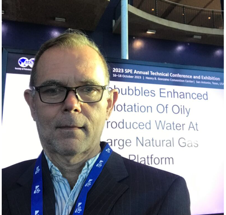 A CWT Global representative at the 2023 SPE Annual Technical Conference in San Antonio, Texas, USA. The screen behind shows a presentation title related to enhanced flotation of oily produced water, highlighting CWT's expertise in water treatment for the oil and gas industry, including the fracking water treatment market.